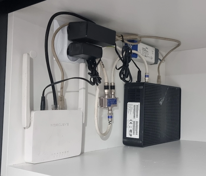 Router, modem i rozgałęźnik antenowy zamontowane na półce